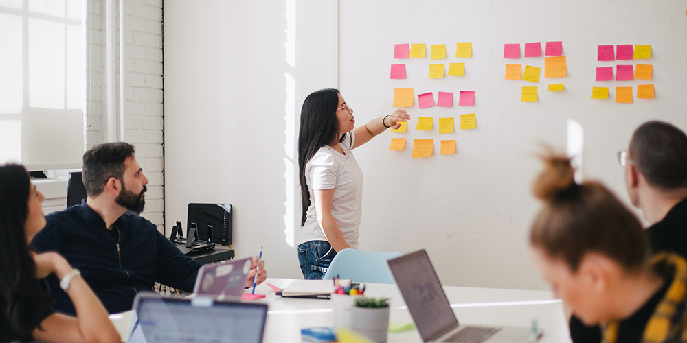 Meeting room with woman pointing at board