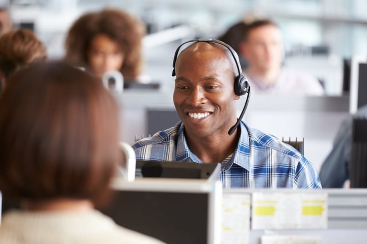 Man working in Contact Centre smiling and wearing a headset