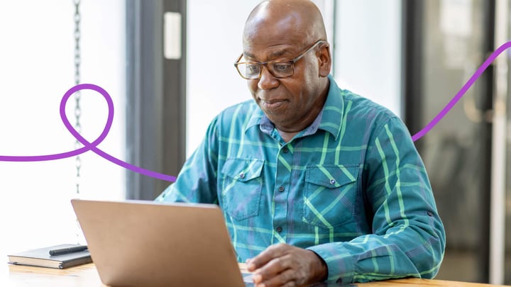 Middle aged man sitting at a table using a laptop