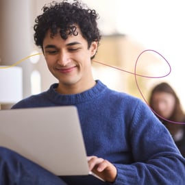 Skills Bootcamps imagery of a young man smiling at his laptop