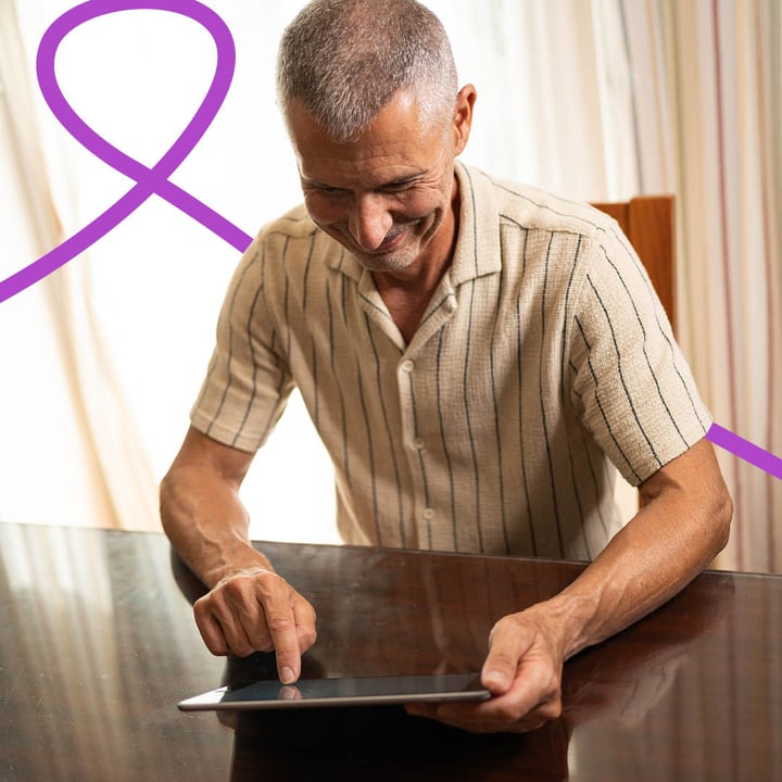 Middle aged man sitting at a table and using a tablet device