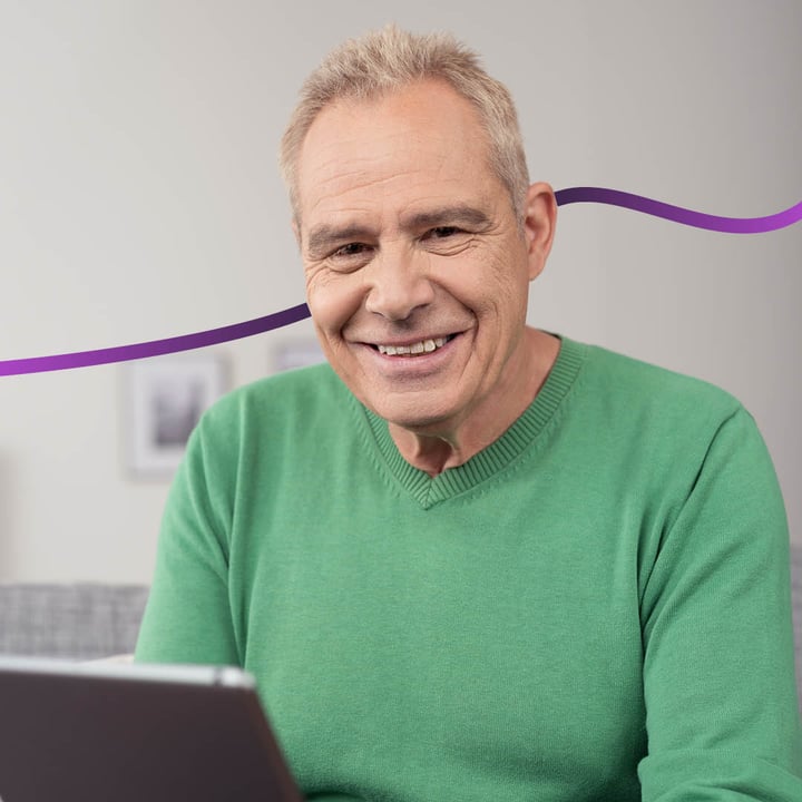 older Caucasian man holding a tablet device and smiling