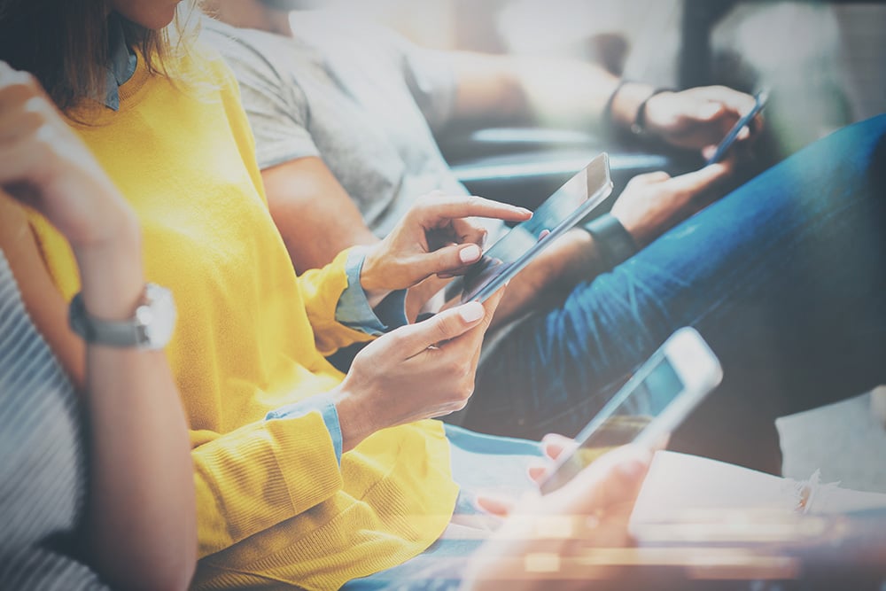 Three people sat down using their phones