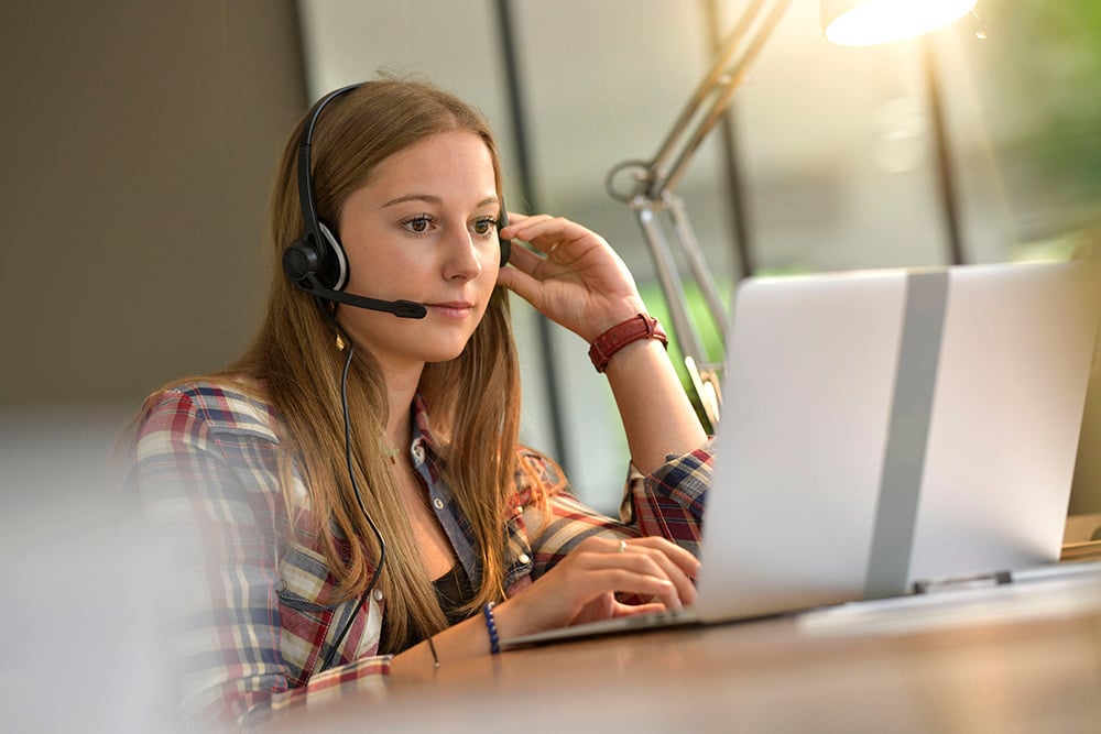 Woman using a laptop with headset