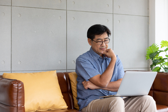 asian senior man using computer laptop at home