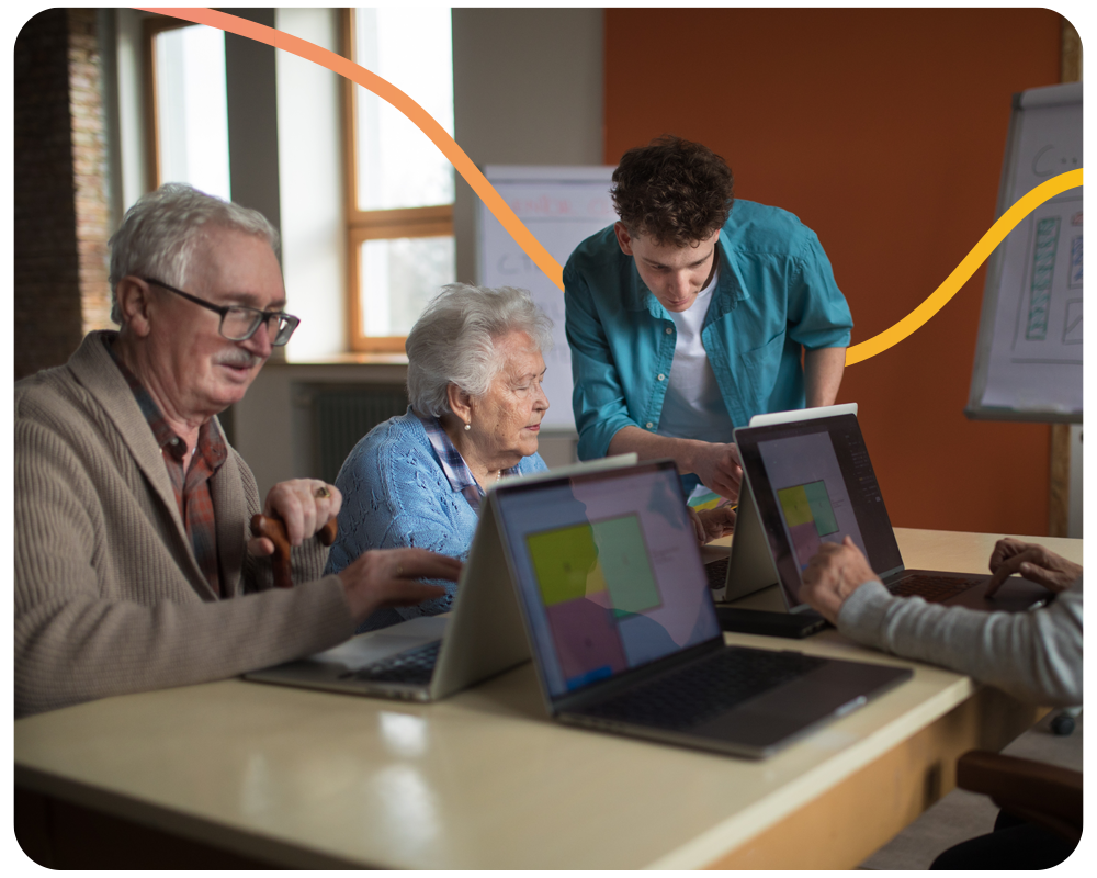 young man explaining how to use laptop to a group of older people