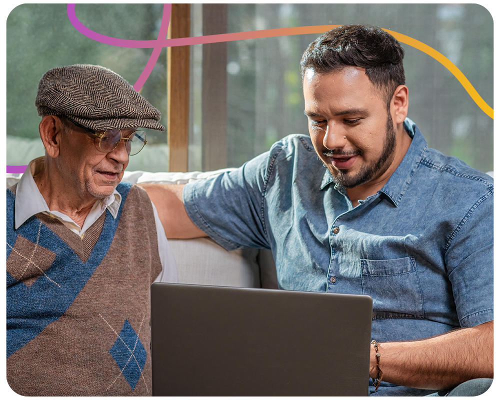Young man teaching older man how to use laptop