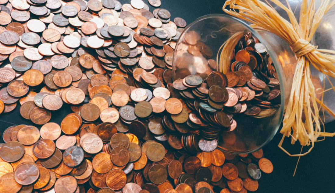 Glass vase with pennies spilled out of it