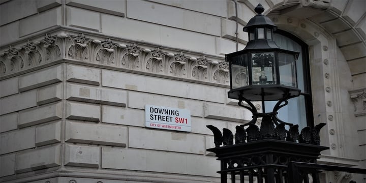 Image of downing street sign on a building. In the foreground a lamp-post is pictured on the right hand side.