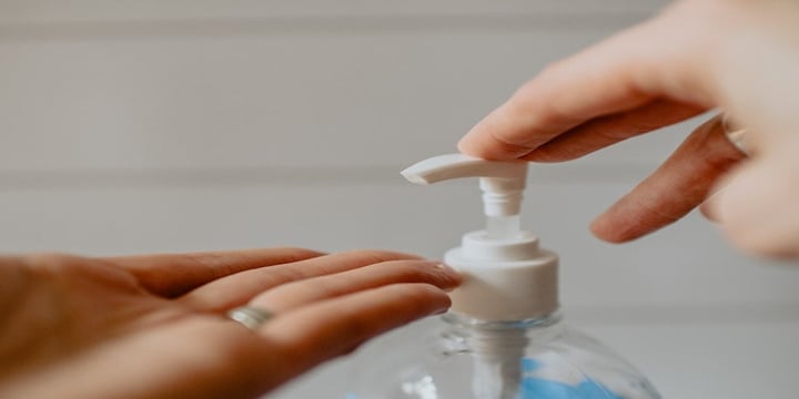 A-hand-pressing-down-on-a-bottle-of-hand-sanitiser.