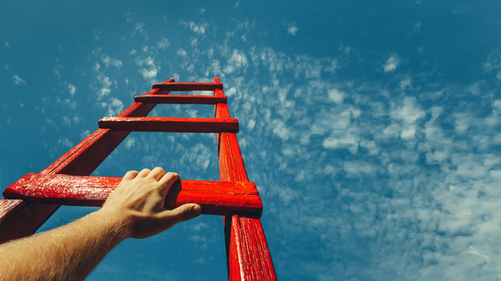 Hand of a man reaching up ladders pointing towards the sky
