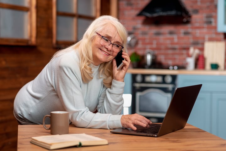 An older lady learning how to use her laptop whilst on the phone to the Digital Helpline