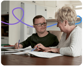 Carer helping person with down syndrom fill out an application