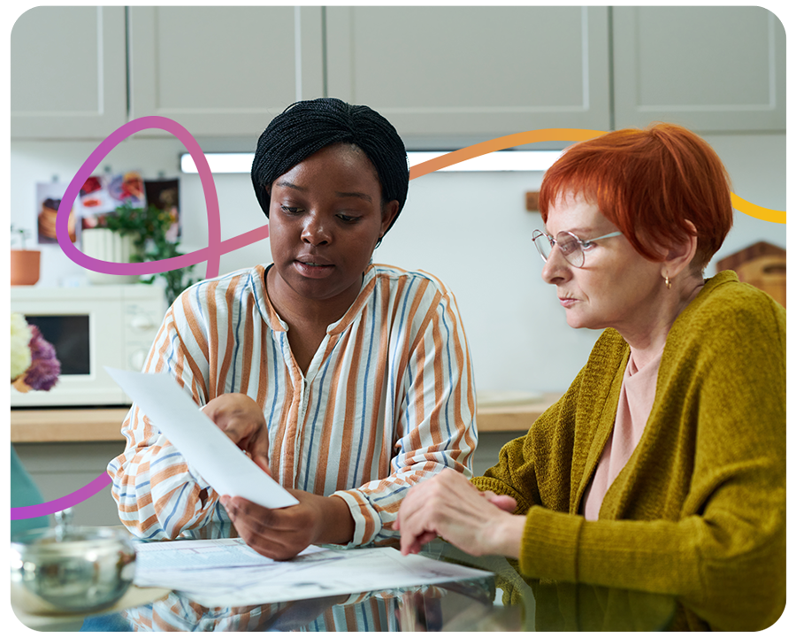 young volunteer sitting at kitchen table together with senior woman and helping with bills