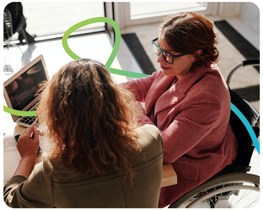 Woman in wheelchair supporting woman to write job applications