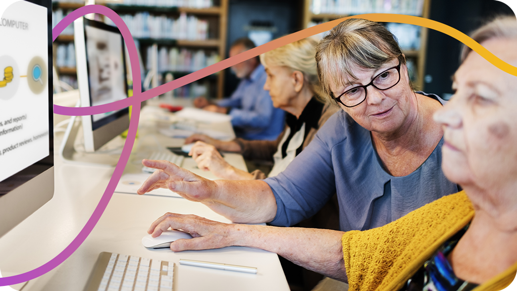 Woman in community centre helping other woman on computer